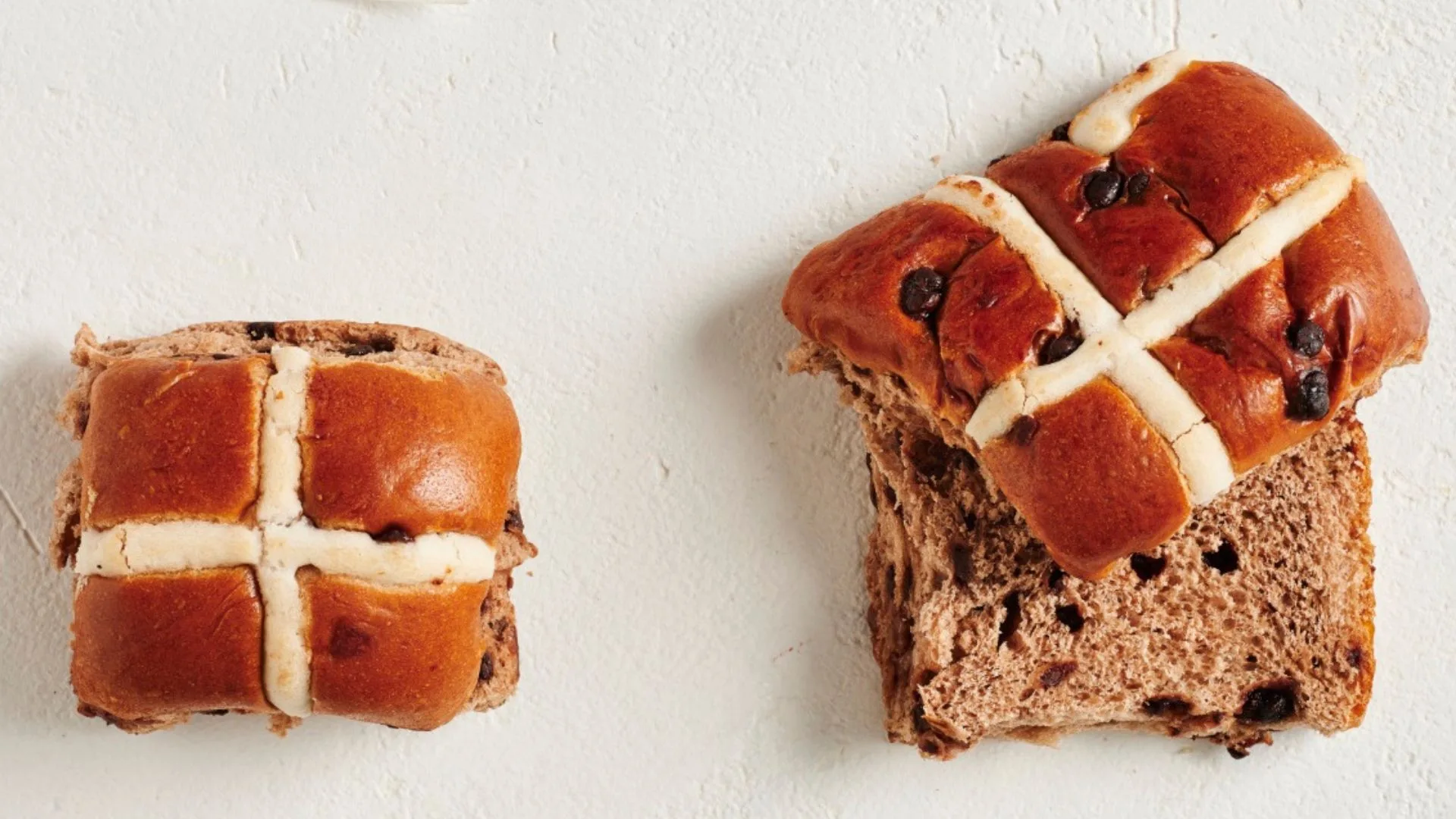 two chocolate hot cross buns, one cut in half