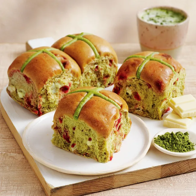 four Matcha & Raspberry Inspired Hot Cross Buns by Coles on a white tile