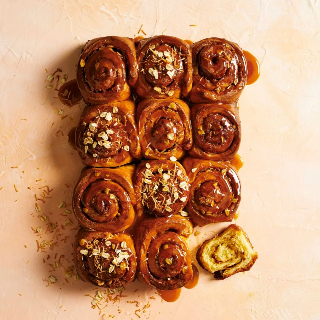 12 anzac biscuit sticky buns on a peach coloured surface