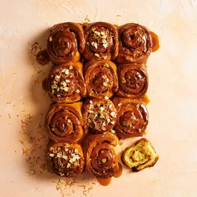 12 anzac biscuit sticky buns on a peach coloured surface