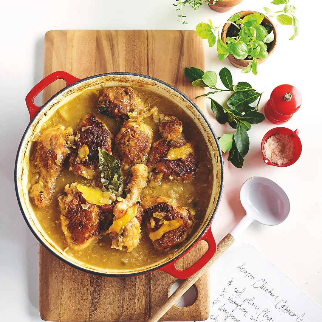 julie goodwin's lemon garlic chicken casserole in a red dish on a wooden chopping board