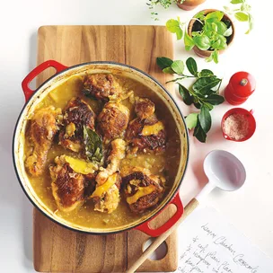 julie goodwin's lemon garlic chicken casserole in a red dish on a wooden chopping board
