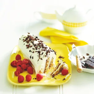 Sherry log on a yellow plate with raspberries and chocolate shavings.