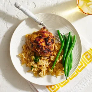 Greek lemon chicken on a white plate with green beans