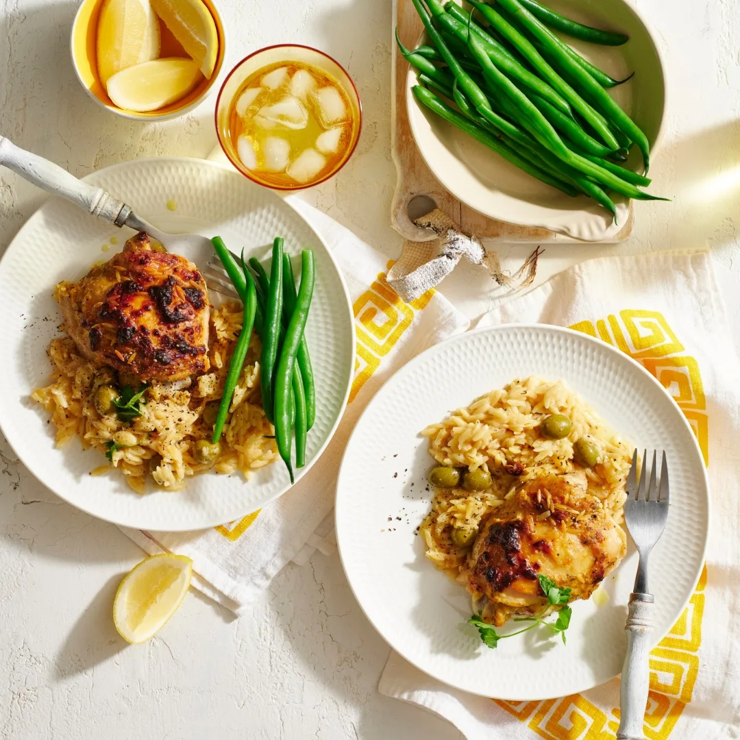 Greek lemon chicken on two white plates with green beans