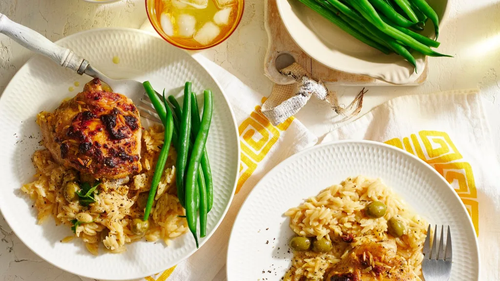 greek lemon chicken on a white serving plate with green beans and pasta