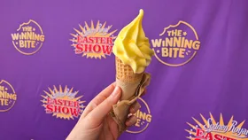 A hand holds an ice-cream cone in front of a purple Sydney Royal Easter Show 2026 banner