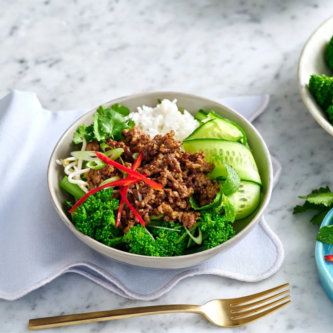 a thai beef rice bowl with a gold fork