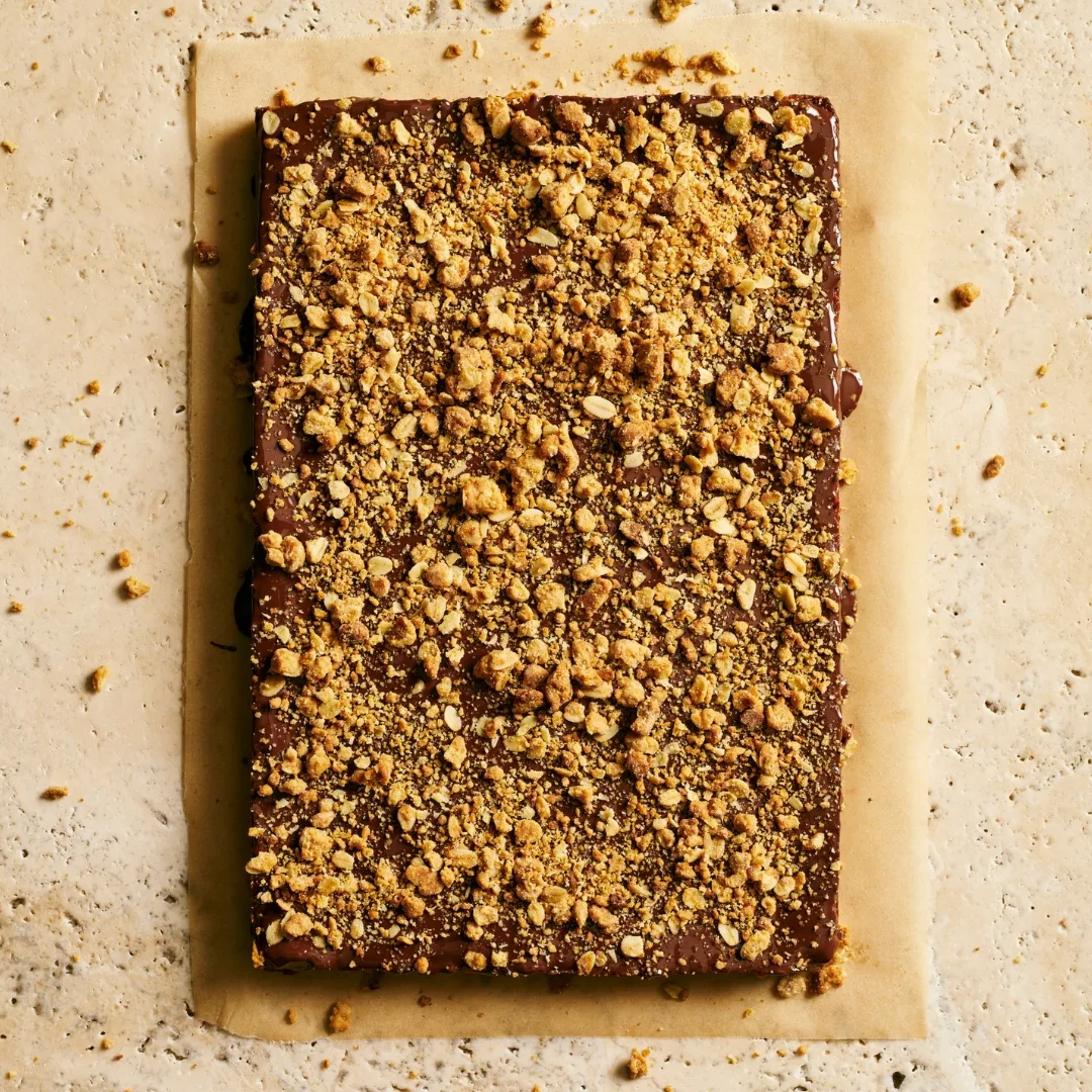 Unsliced anzac caramel slice on a sheet of baking paper