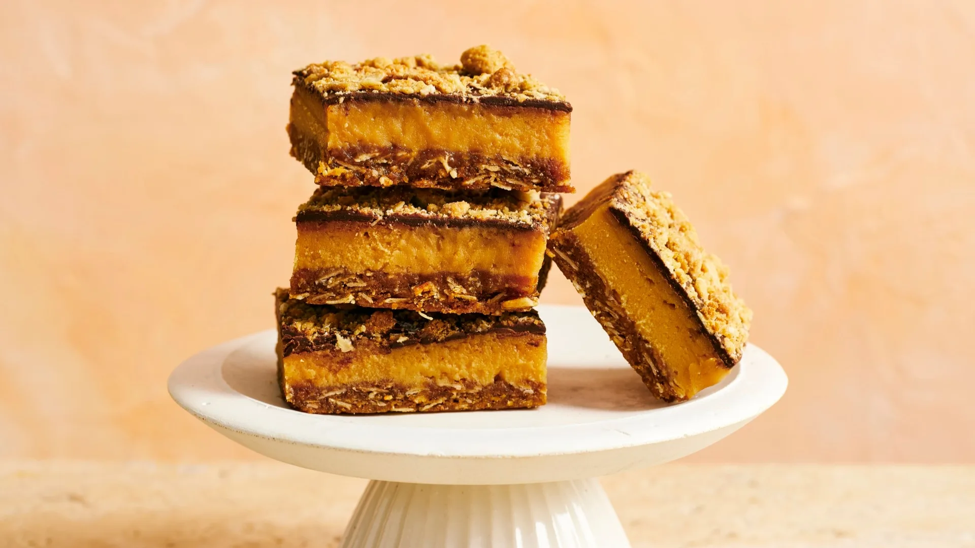 anzac caramel slice cut into pieces on a white cake stand
