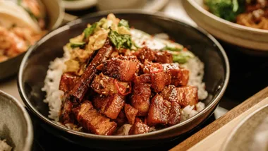 Glazed cubes of Korean braised pork belly piled on white rice, garnished with fresh red chili, sautéed wombok and sliced pickled cucumber. Article - Korean meal kits Australia