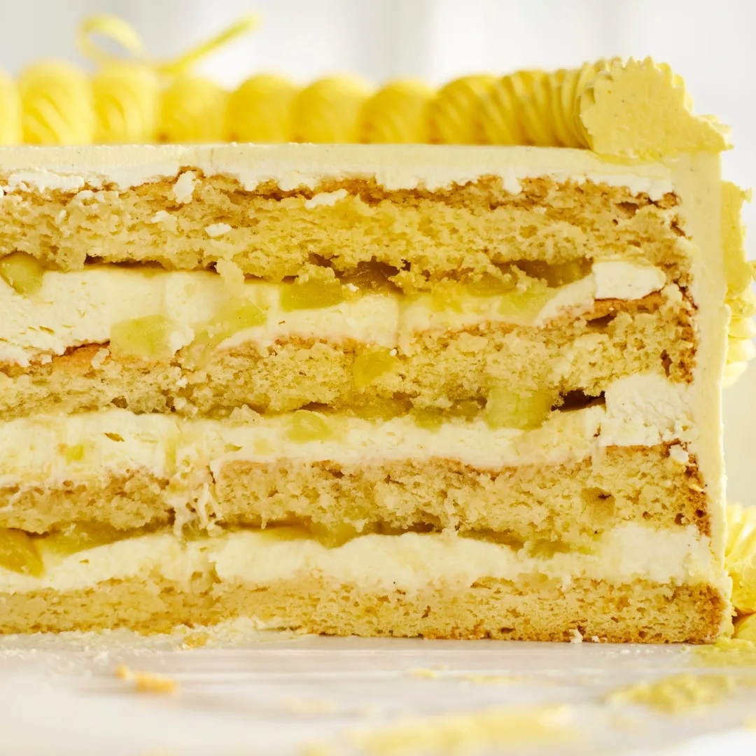 four-layered vintage cake with yellow piped icing and buttercream cut in half