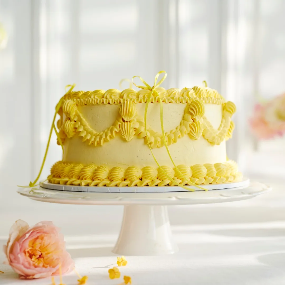 vintage cake with yellow piped icing on a white cake stand