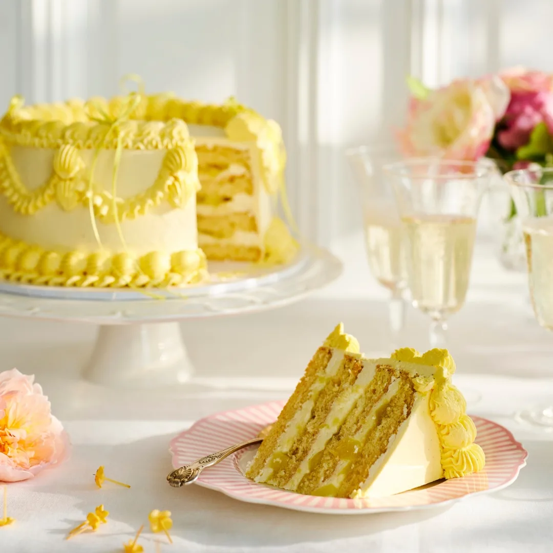 slice of a layered vintage cake with yellow piped icing on a pink plate