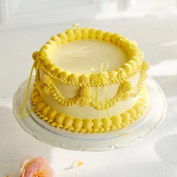 vintage cake with yellow piped icing on a white cake stand