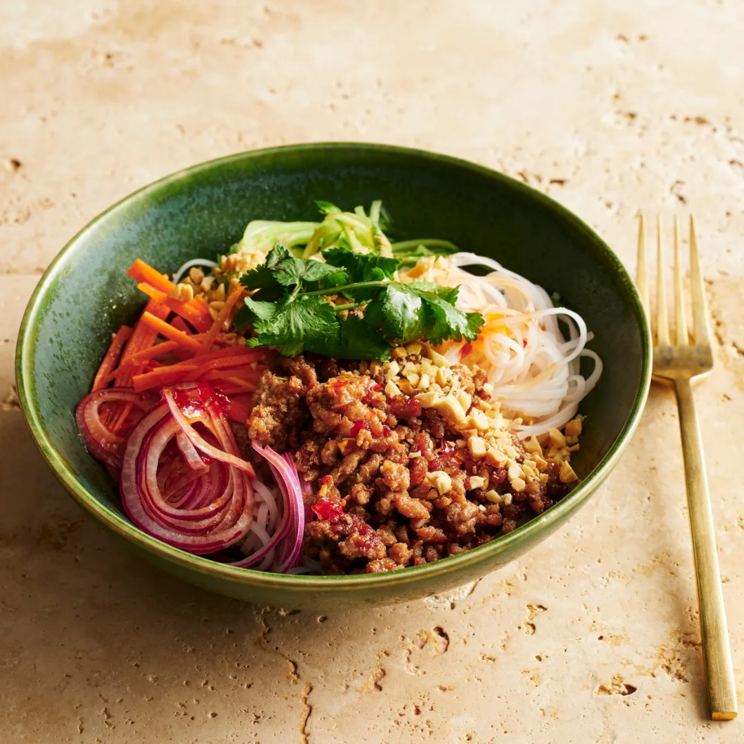 vietnamese minced pork noodles in a green bowl with a fork