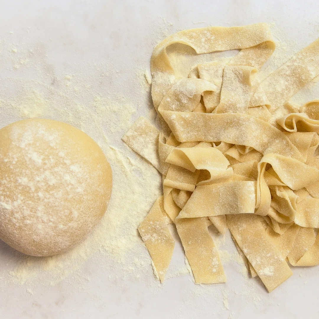 a ball of fresh egg pasta dough and strips cut into pappardelle