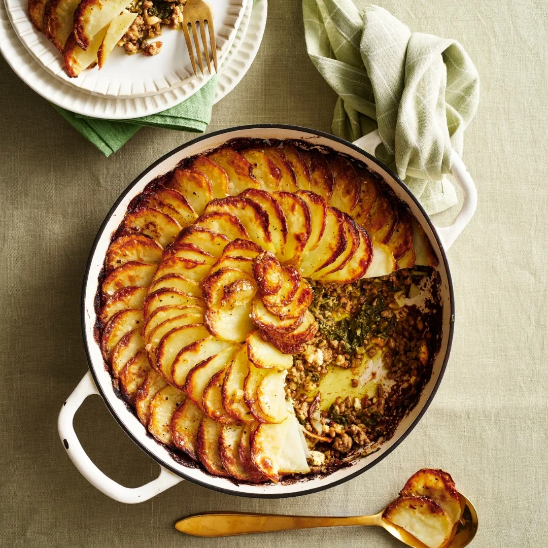 Lamb mince, silverbeet & potato pie in a round dish with a scoop taken out