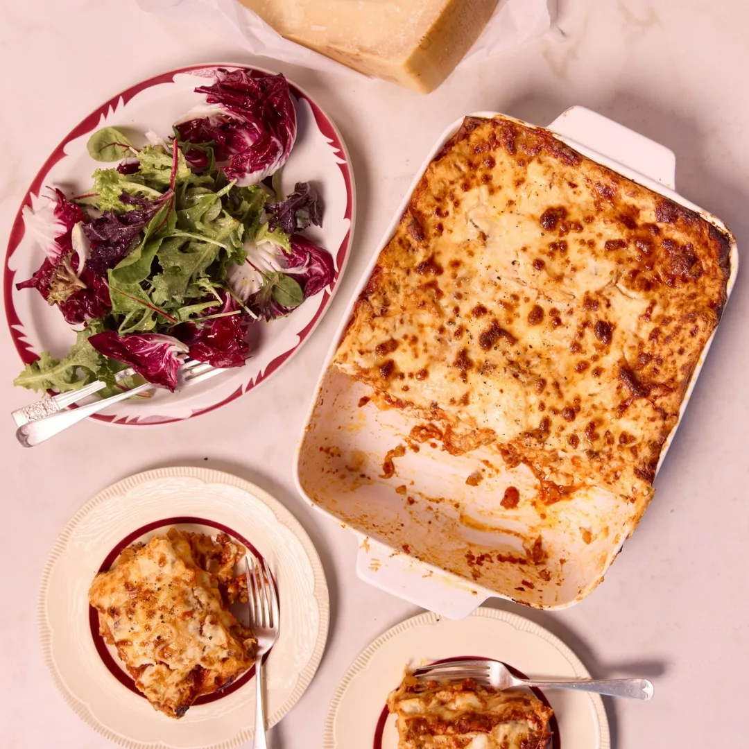 lasagne in a white dish with a salad