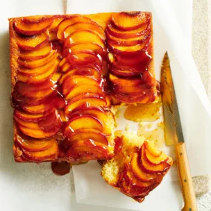 peach cake in a square shape with a knife