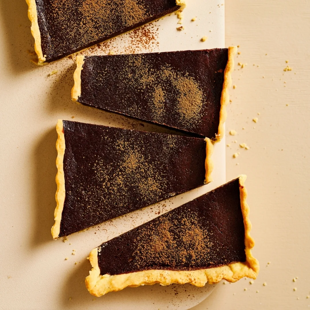 Rich chocolate tart, cut into four big pieces diagonally and dusted with cocoa powder.