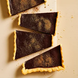 Rich chocolate tart, cut into four big pieces diagonally and dusted with cocoa powder.
