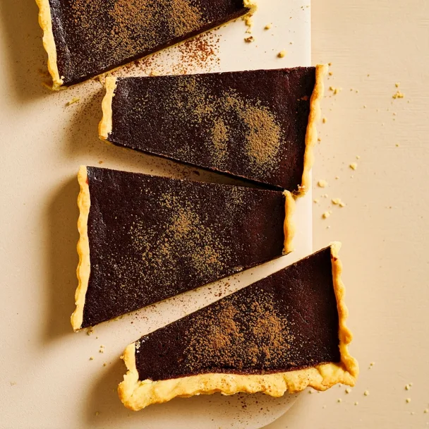 Rich chocolate tart, cut into four big pieces diagonally and dusted with cocoa powder.