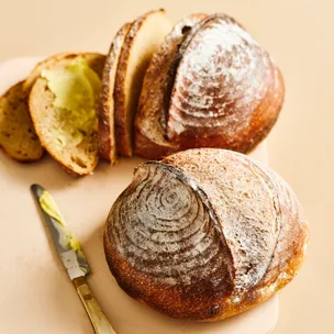 Two sourdough boules with some buttered slices nearby
