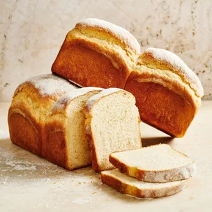 Two white bread loaves with slices cut from the front loaf