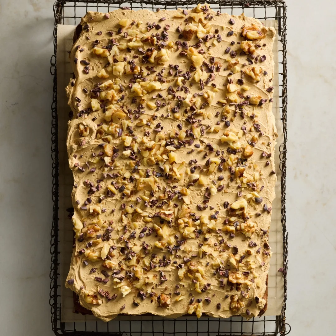 coffee sheet cake topped with icing, walnuts and cocoa nibs