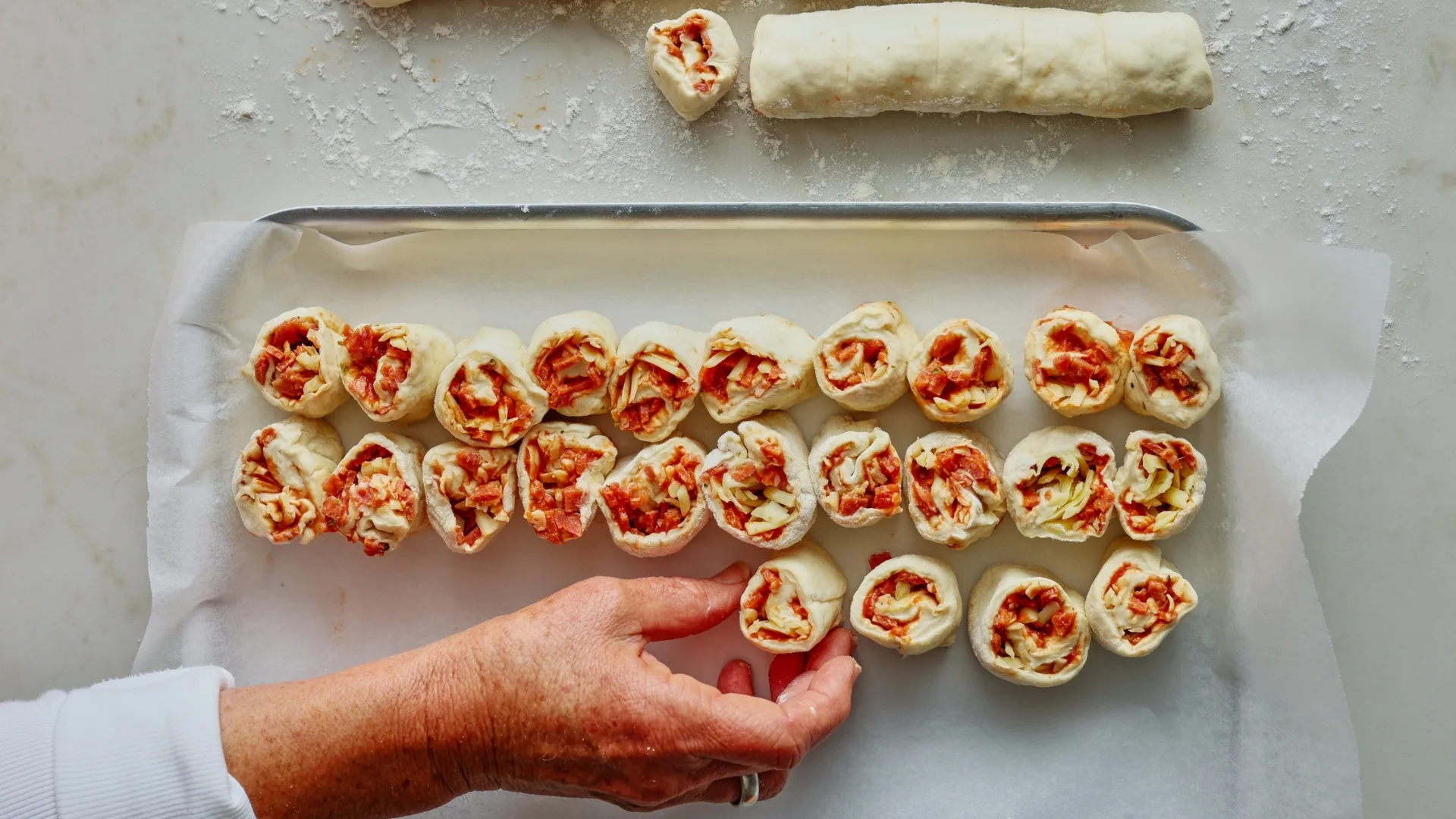 placing mini pizza scrolls onto a tray