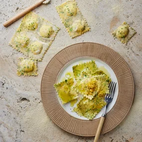 Parmigiano Regginao ravioli in a bowl with uncooked ravioli on the bench