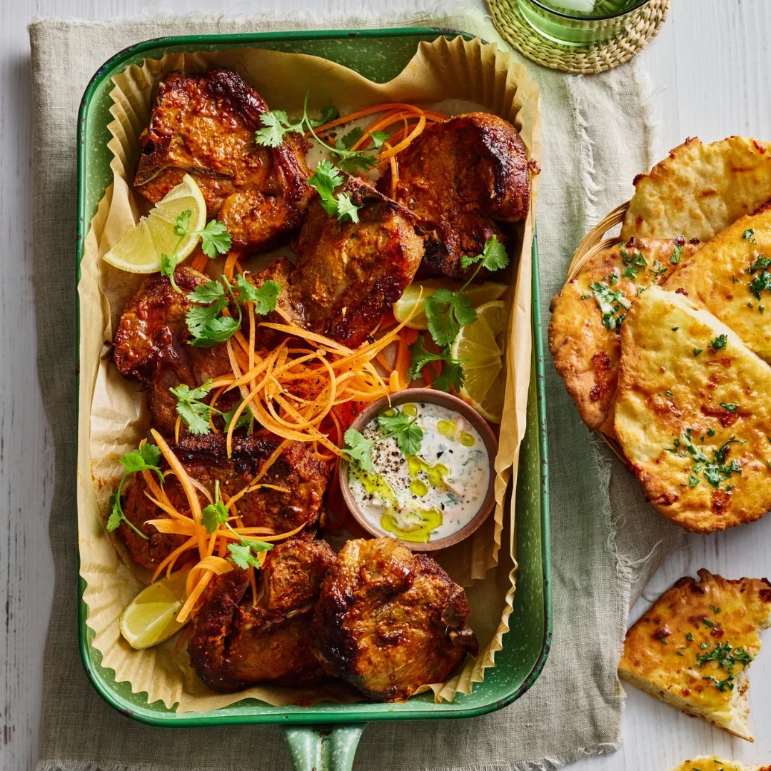 air fryer tandoori lamb chops in a green baking dish with a bowl of flatbread