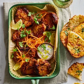 air fryer tandoori lamb chops in a green baking dish with a bowl of flatbread