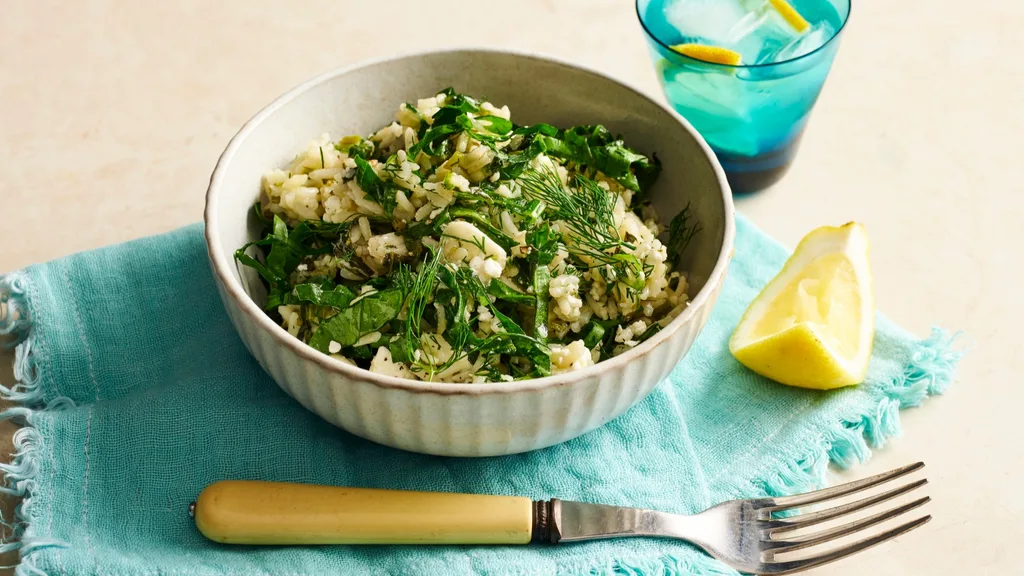 greek lemon and dill rice in a bowl with a fork and lemon wedge