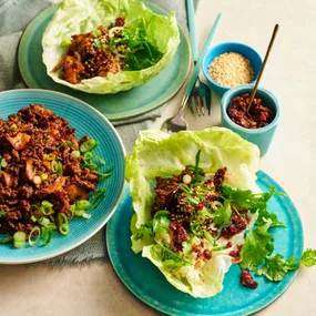 two lettuce cups with san choy bow beef, and a third plate with beef mixture