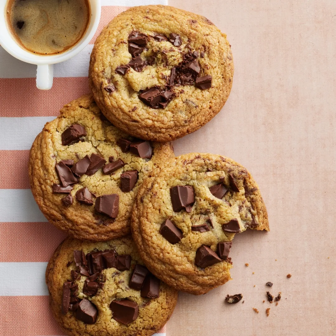 four small batch chocolate chip cookies with a mug of coffee