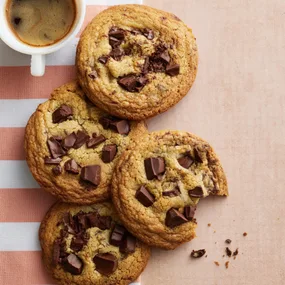 four small batch chocolate chip cookies with a mug of coffee