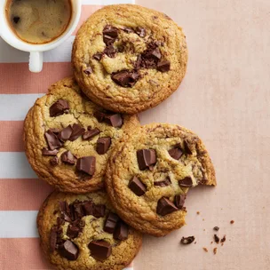 four small batch chocolate chip cookies with a mug of coffee