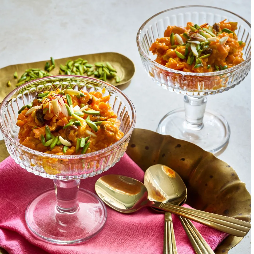 Carrot Halwa in two serving glasses, topped with chopped pistachios