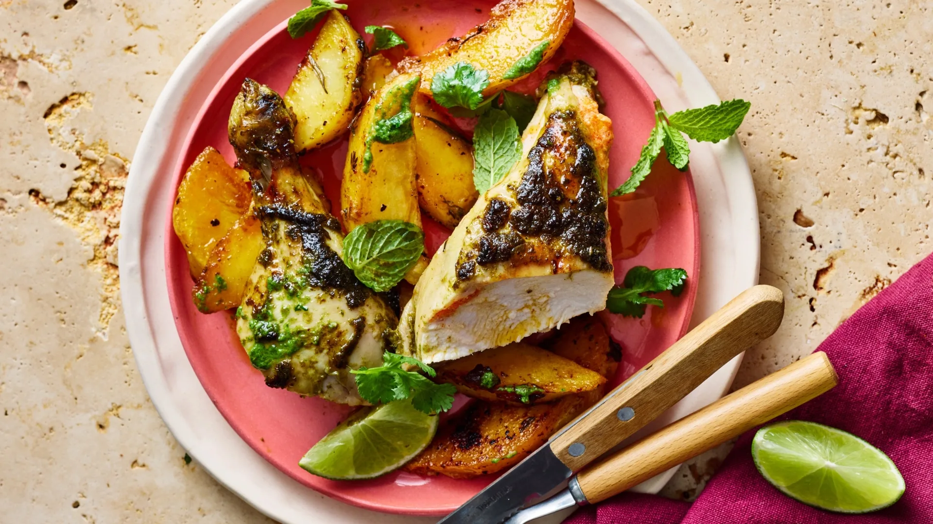 plate of roast chicken with green chutney marinade, and potatoes and lime wedges