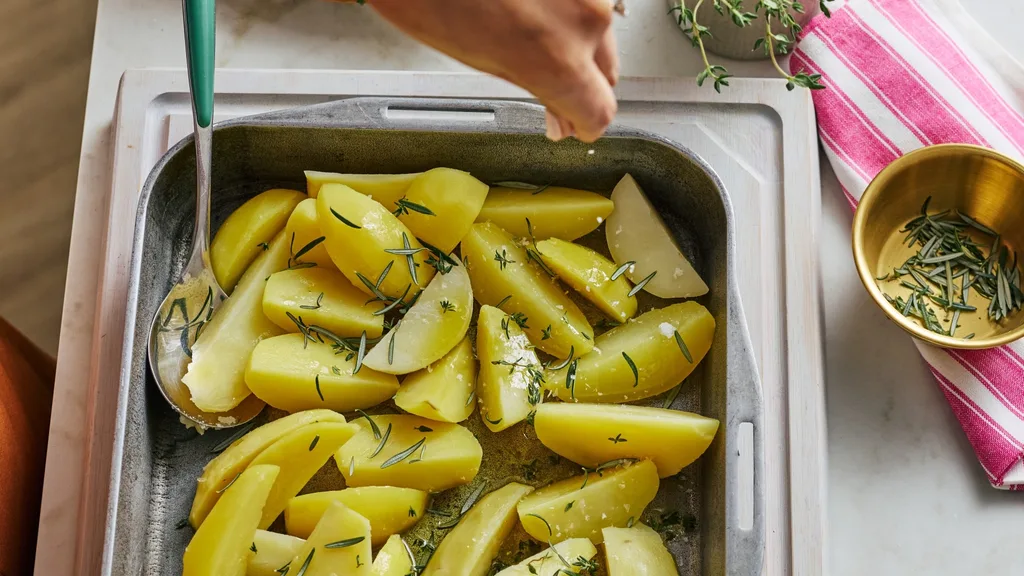 potato wedges in a tray sprinkled with rosemary and salt