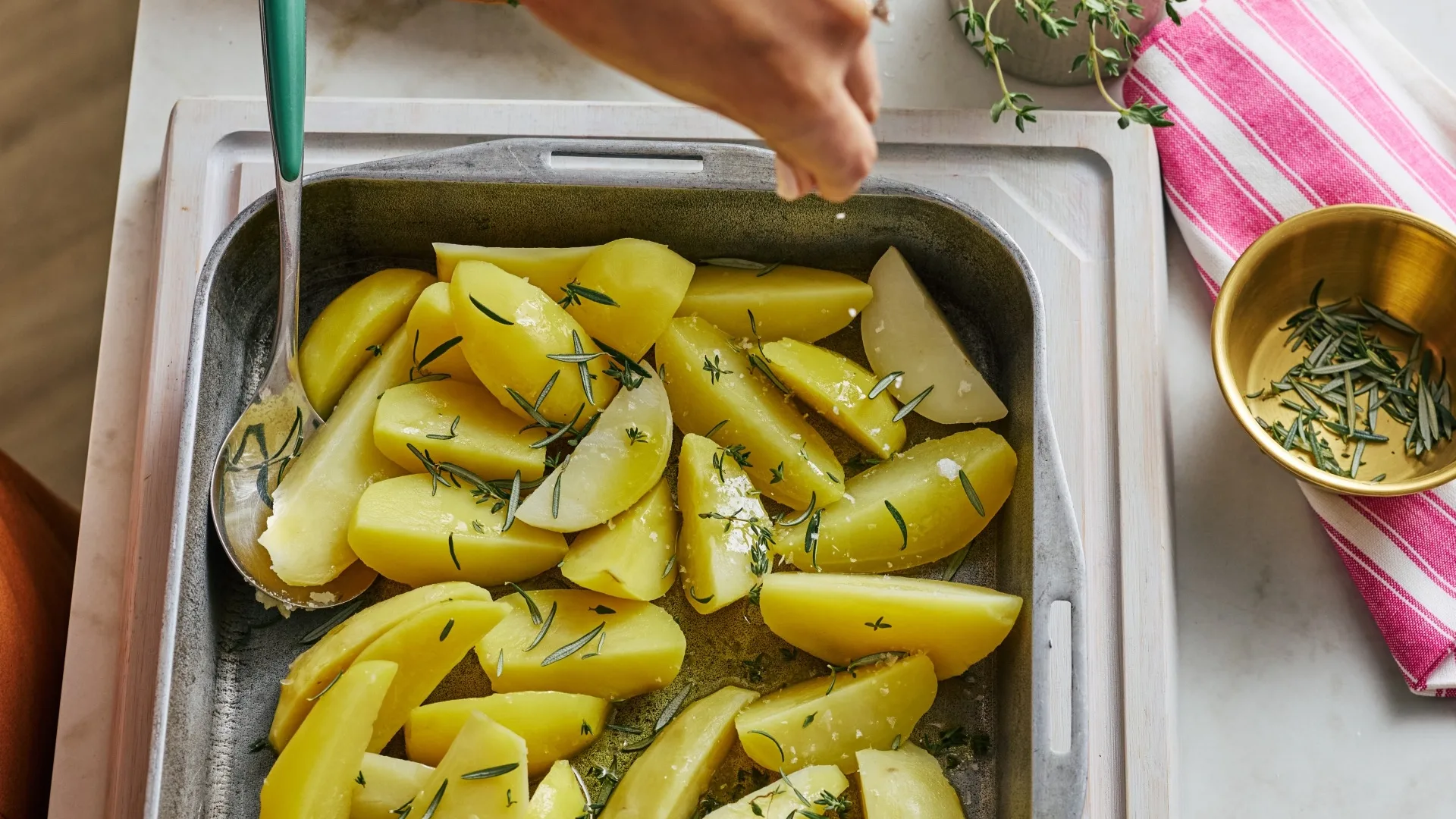 potato wedges in a tray sprinkled with rosemary and salt