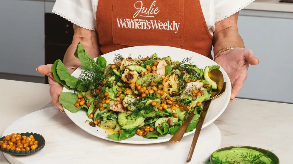 Julie Goodwin's holding a platter of her roasted cauliflower salad with chicken with serving utensils