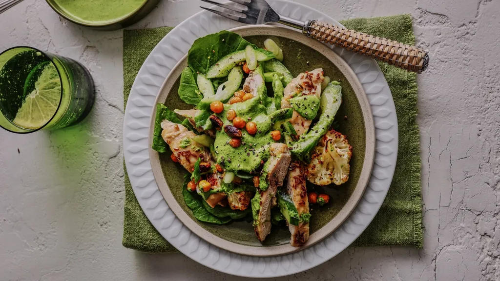 plate of roasted cauliflower salad with chicken, topped with a green sauce