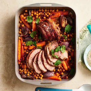 mini lamb roasts in a tray with carrots and chickpeas