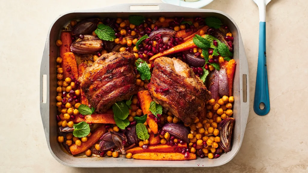 mini lamb roasts in a tray with carrots and chickpeas