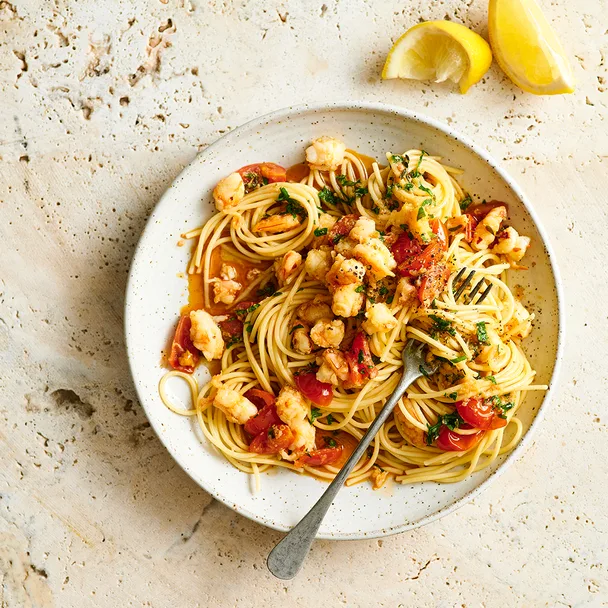 Bowl of prawn spaghettoni topped with cherry tomatoes, garlic, fresh parsley