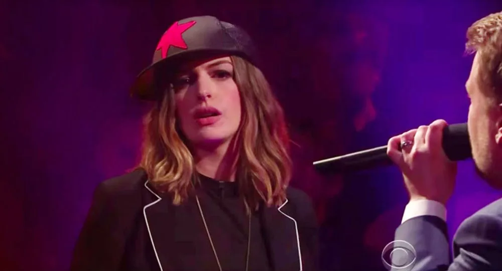Anne Hathaway wears a cap with a red star, performing in a rap battle on The Late Late Show with James Corden.