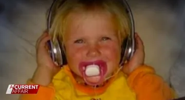 A small child wearing large headphones and a pacifier, with the "A Current Affair" logo in the bottom left corner.